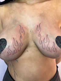 a woman with a tattoo of flames on her breasts