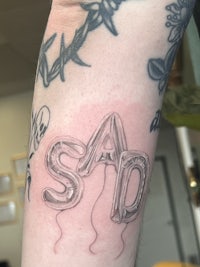 a tattoo of the word sad on a person's arm