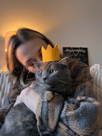 a woman wearing a yellow crown with a gray cat