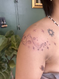 a woman's shoulder tattoo with stars and planets